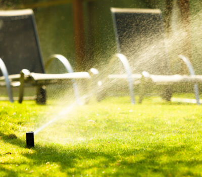 Gardening. Lawn sprinkler spraying water over green grass. Irrigation system - technique of watering in the garden.